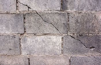 Cracked concrete block wall with weathered gray surface and visible mortar lines